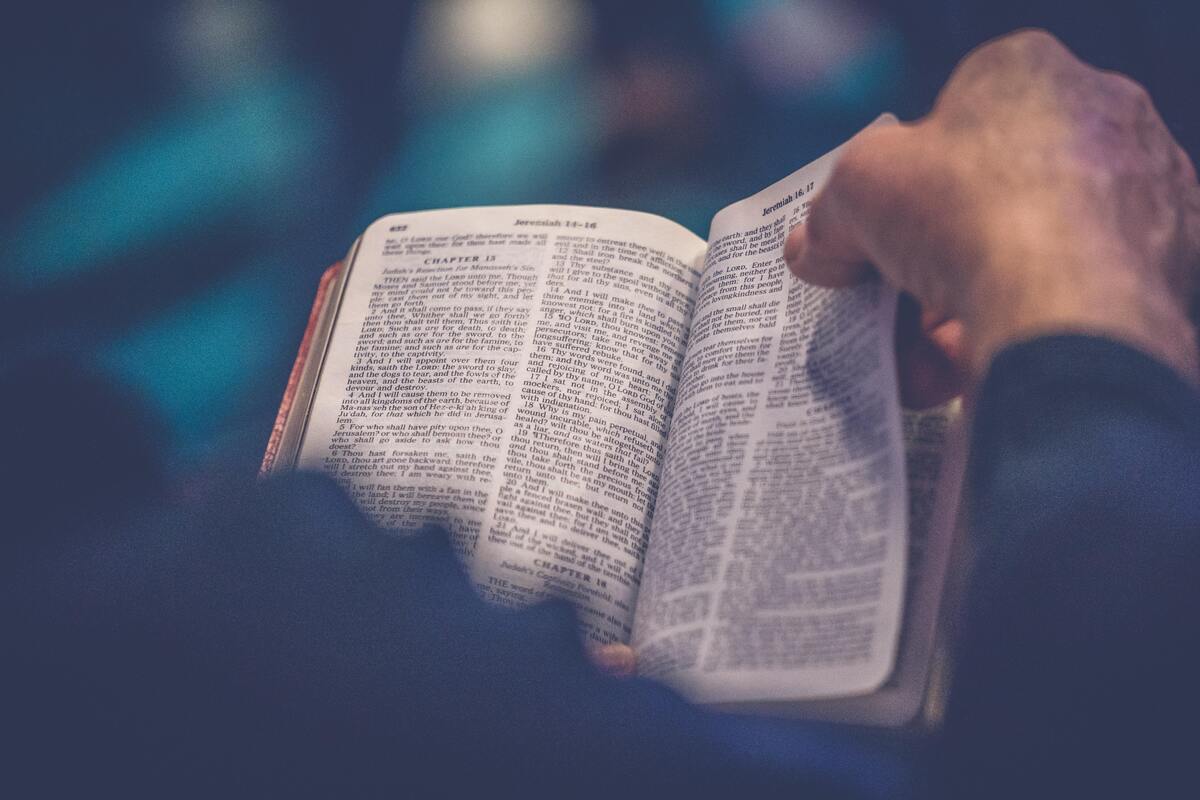 Homem passando as páginas de uma bíblia. 
