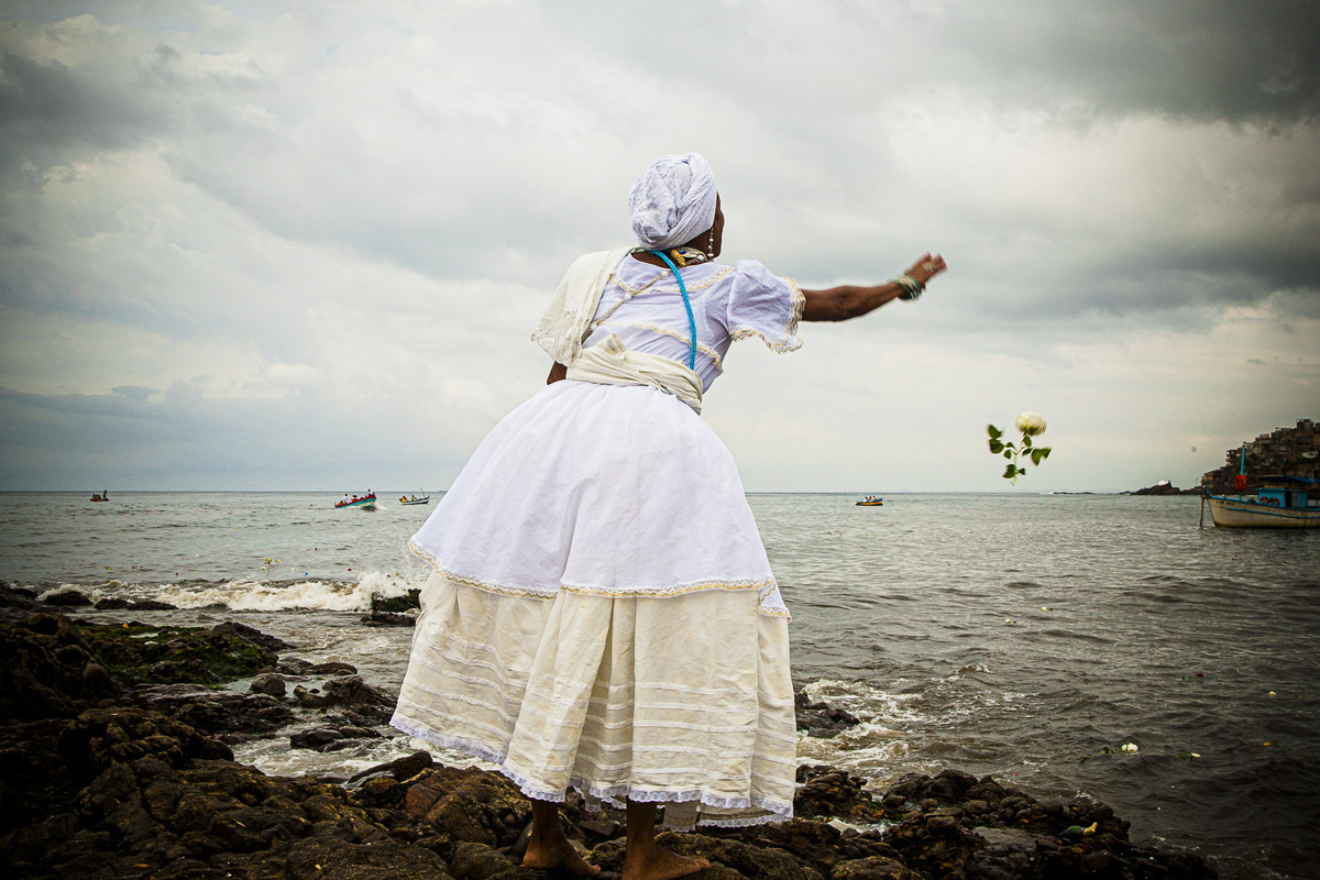 Adepta de religião de matriz africana jogando flores no mar