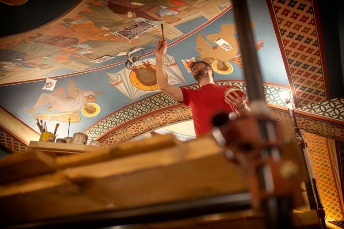 Homem pintando teto de igreja em reforma