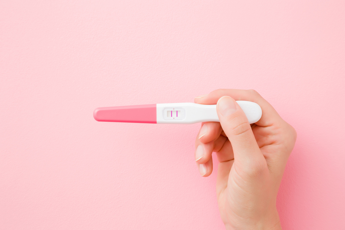 Teste de gravidez positivo em fundo rosa