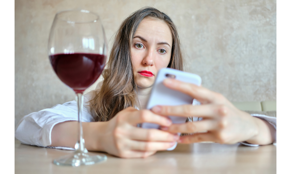 Mulher frustrada com um celular e uma taça de vinho.