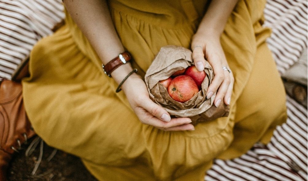 Mulher segurando sacola com maçãs vermelhas