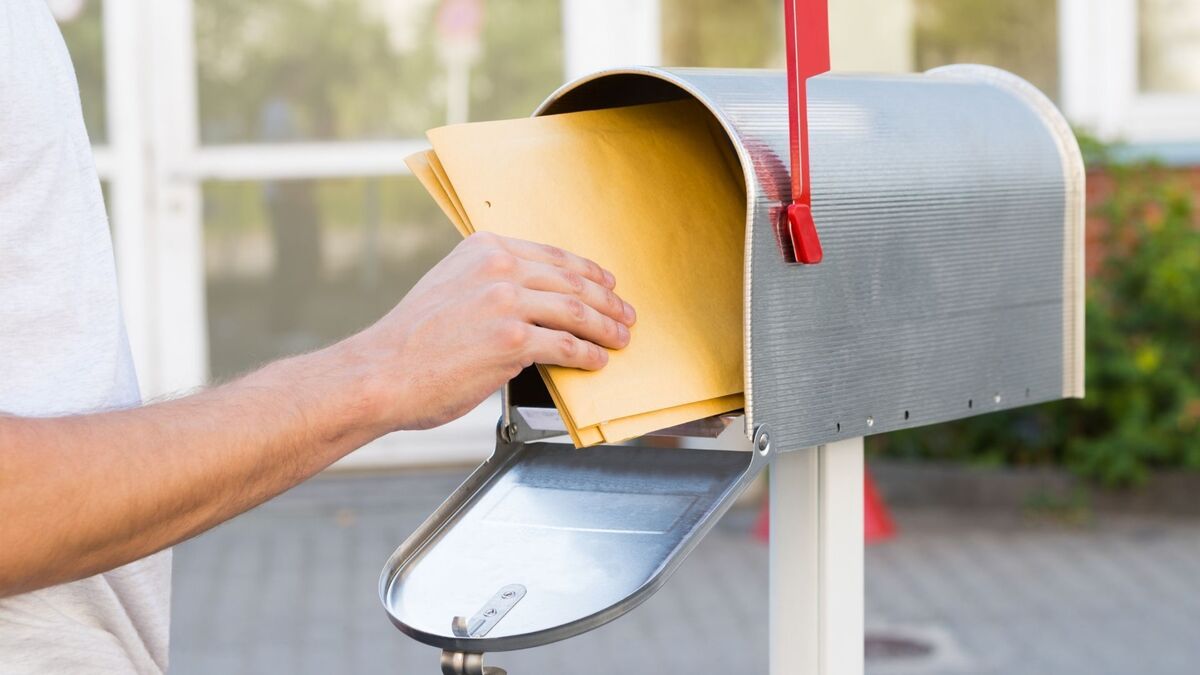 Pessoa colocando cartas em uma caixa de correio.