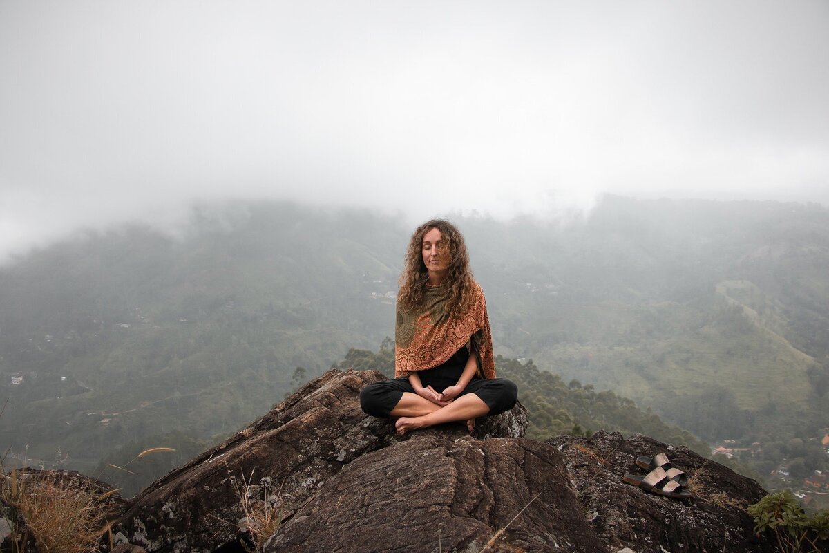 Mulher meditando em uma montanha.