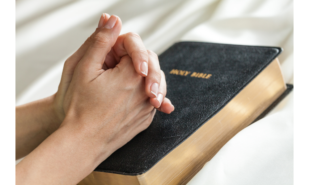 Mãos em oração sobre uma bíblia.