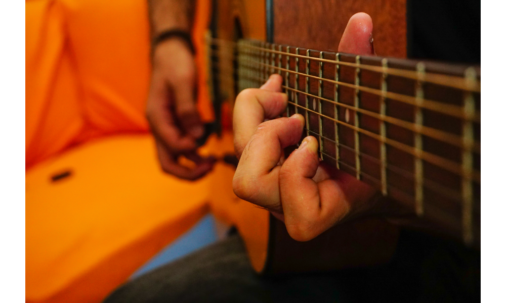 Pessoa tocando um violão com foco em suas cordas.