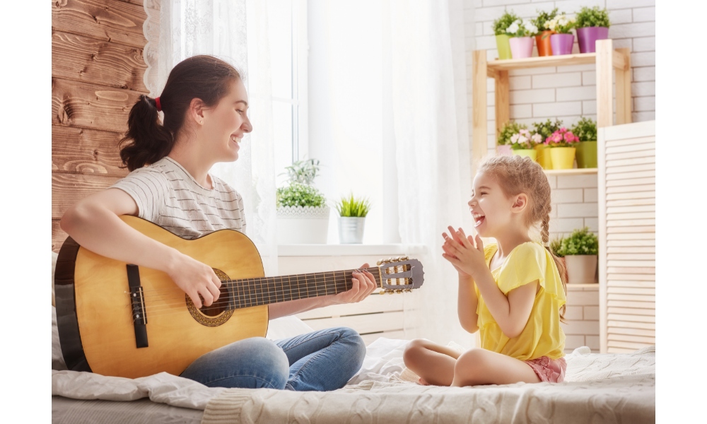 Mulher tocando violão com sua filha pequena.