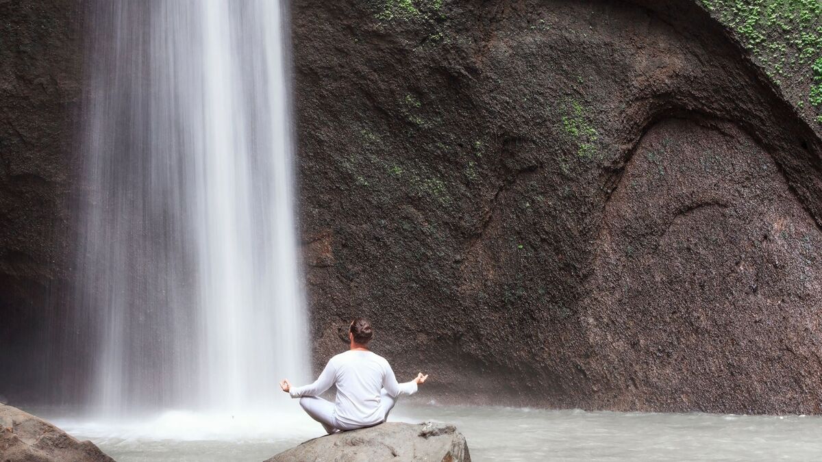 Pessoa meditando em uma cachoeira.