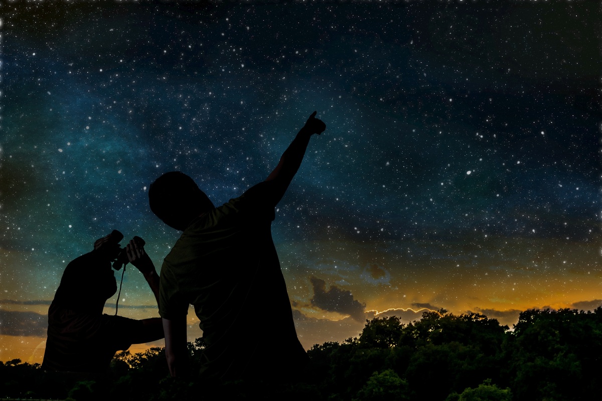 Sombra de duas pessoas observando o céu estrelado juntas. 