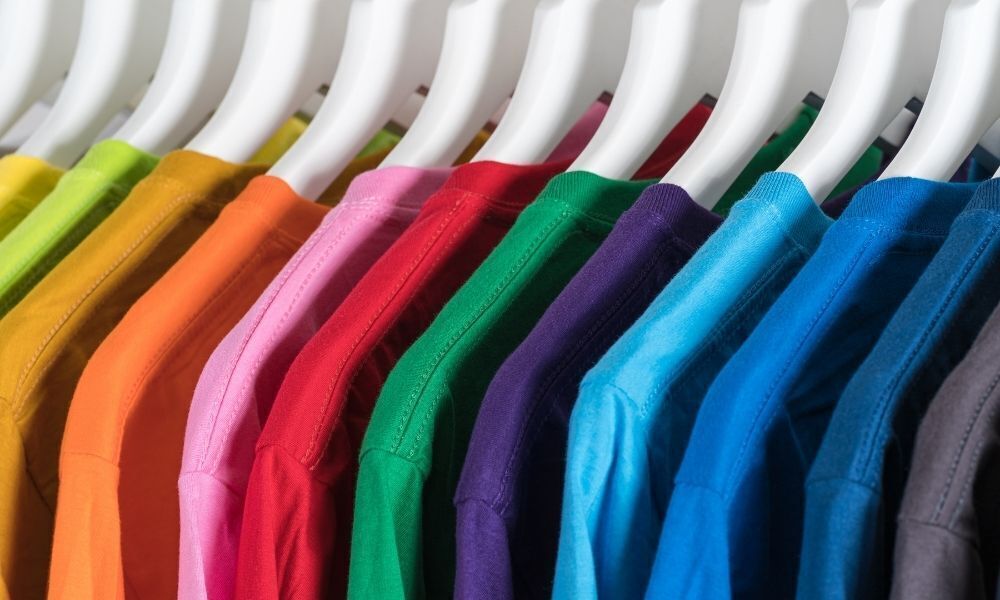 Cabides com camisetas coloridas em guarda-roupa.