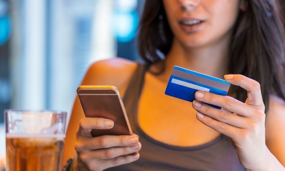 Mulher fazendo compra com cartão de crédito pelo celular.