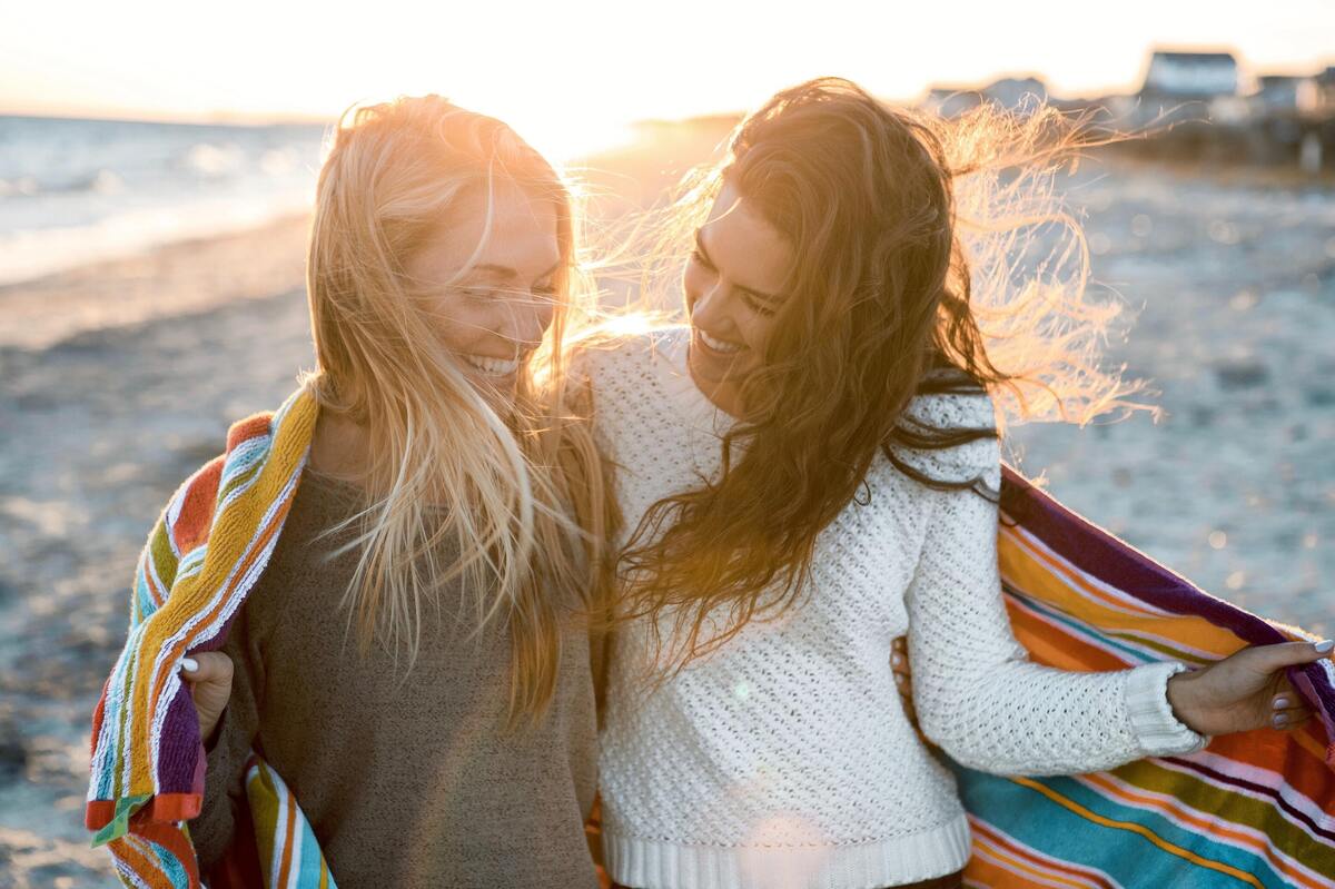 Duas mulheres abraçadas na praia.