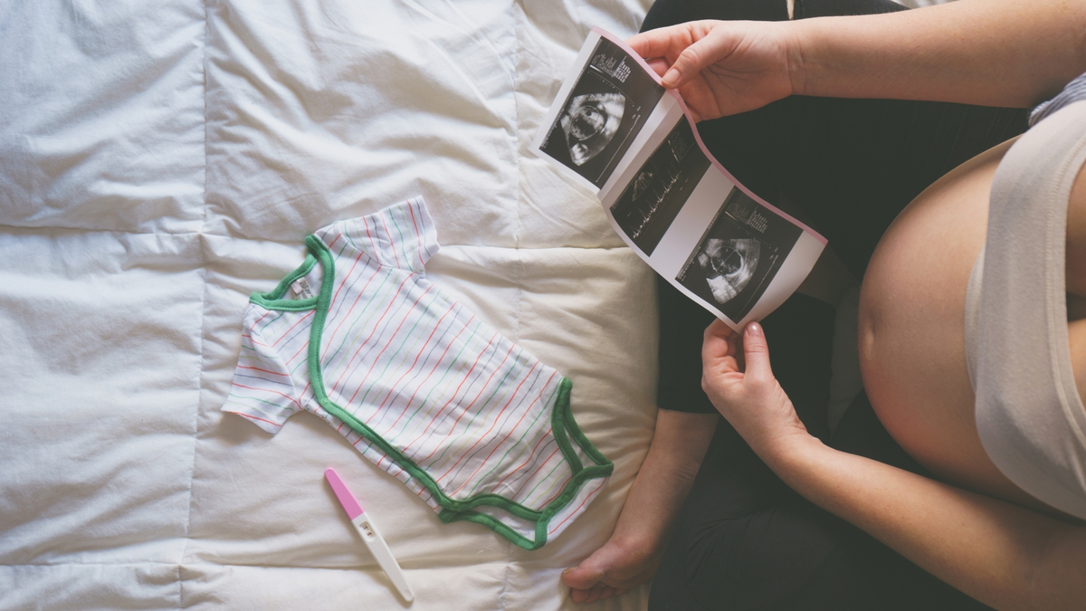Mulher olhando teste de gravidez e ultrassom. 