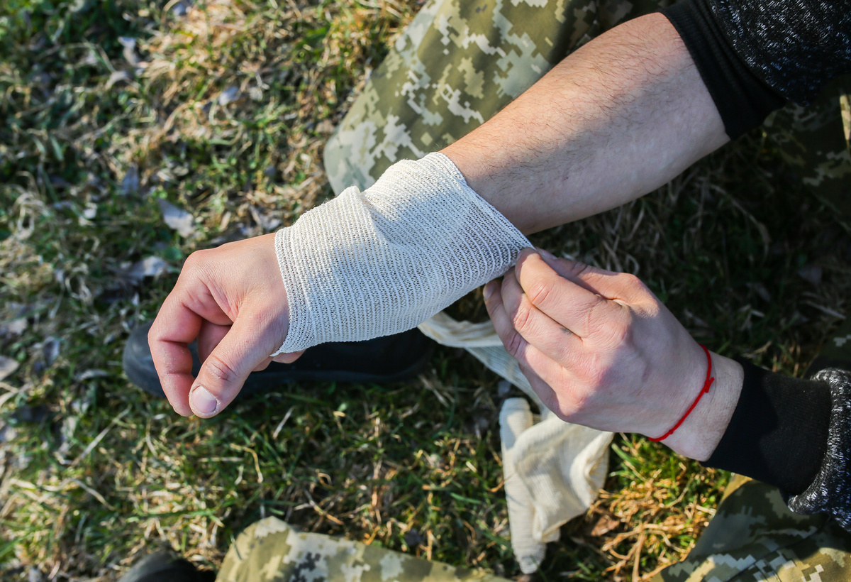 Pessoa com braço enfaixado após mutilação.