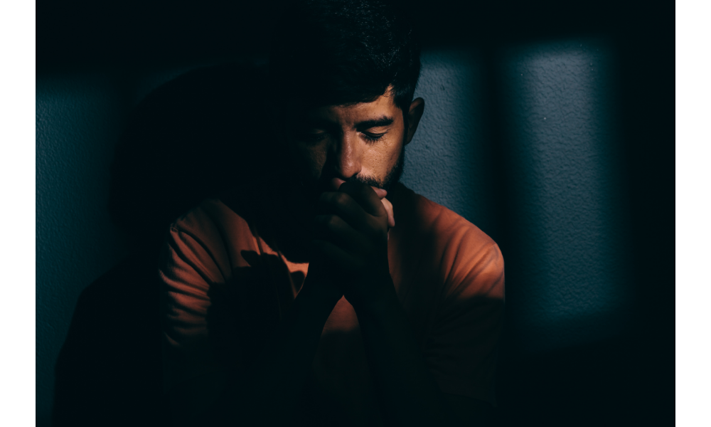 Homem em um ambiente escuro deprimido ou orando.