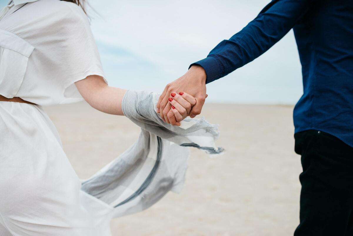 Casal de mãos dadas na praia. 