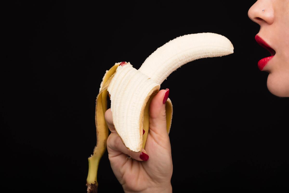 Mulher comendo uma banana.