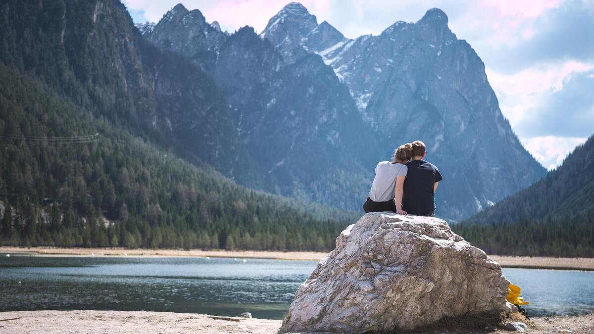 Casal sentado em uma pedra, abraçado.