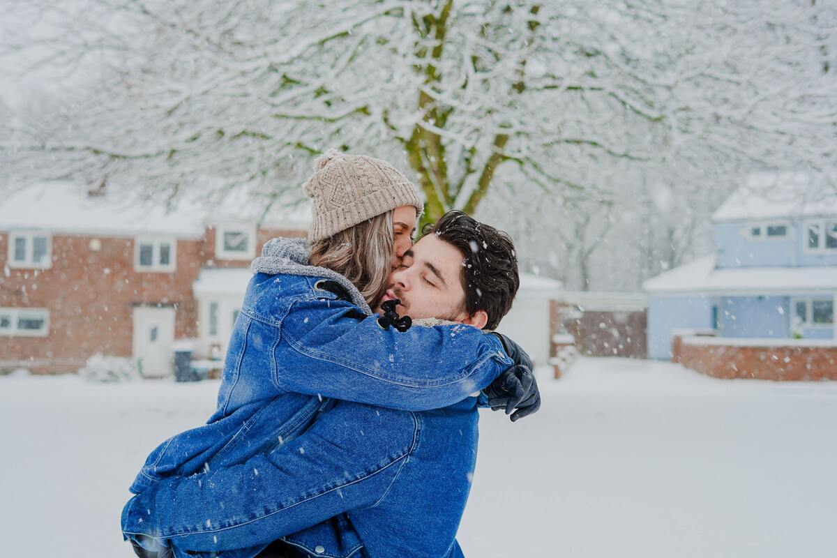 Casal se abraçando na neve.