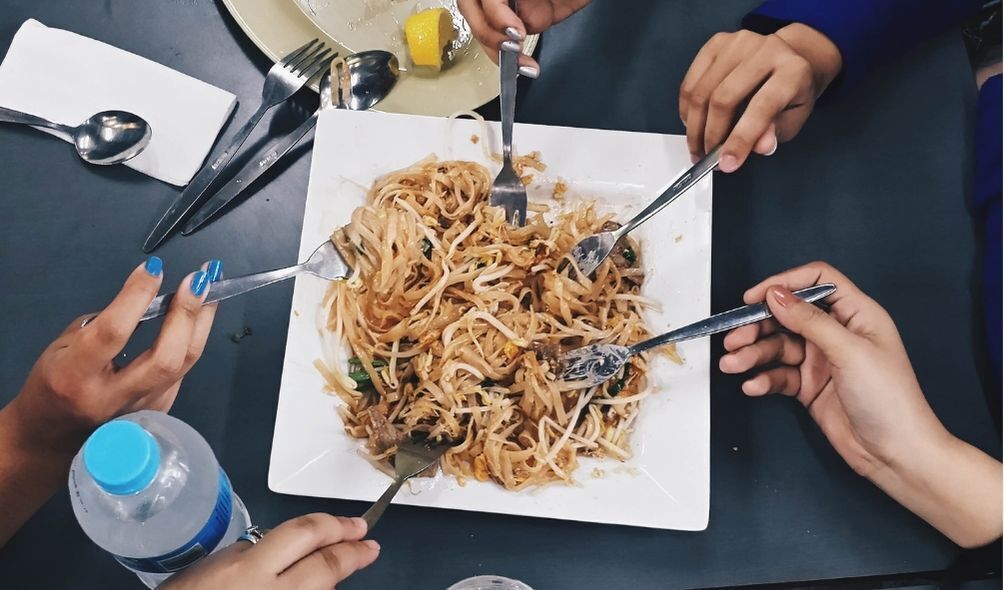 Pessoas compartilhando prato de macarrão asiático