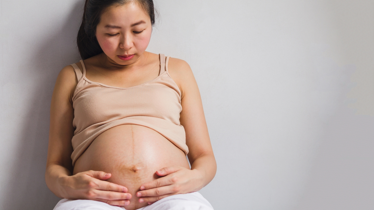 Mulher grávida olhando para a barriga.