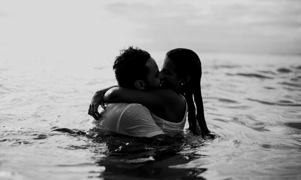 Casal se beijando no mar.