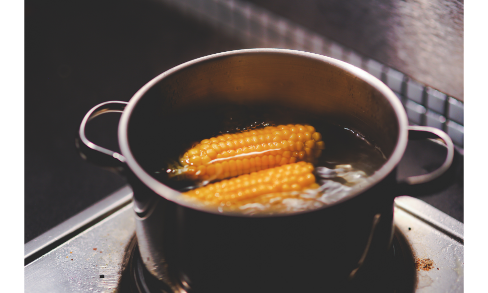Espigas de milho cozinhando em uma panela.