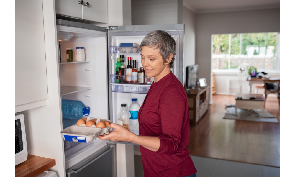 Mulher colocando comida em uma geladeira.