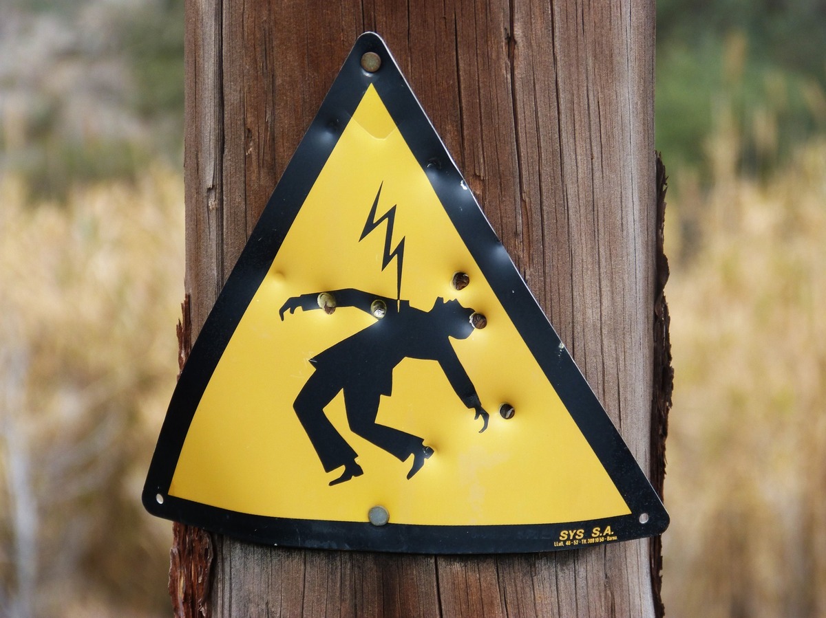 Placa com ilustração de pessoa levando choque elétrico.