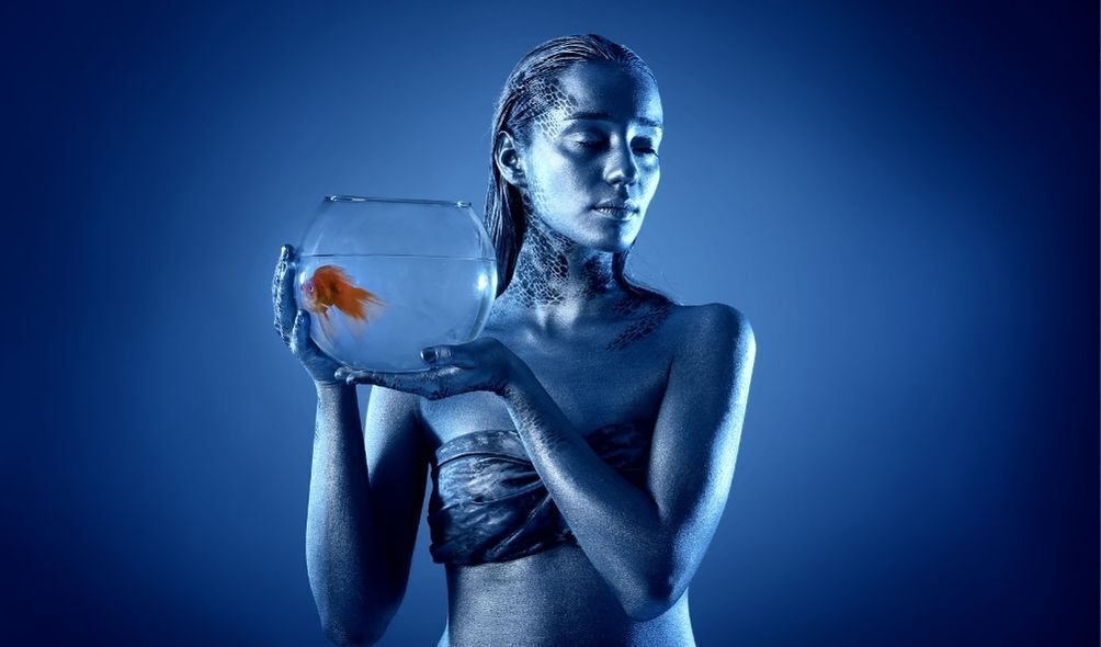 Mulher segurando um aquário com um peixe