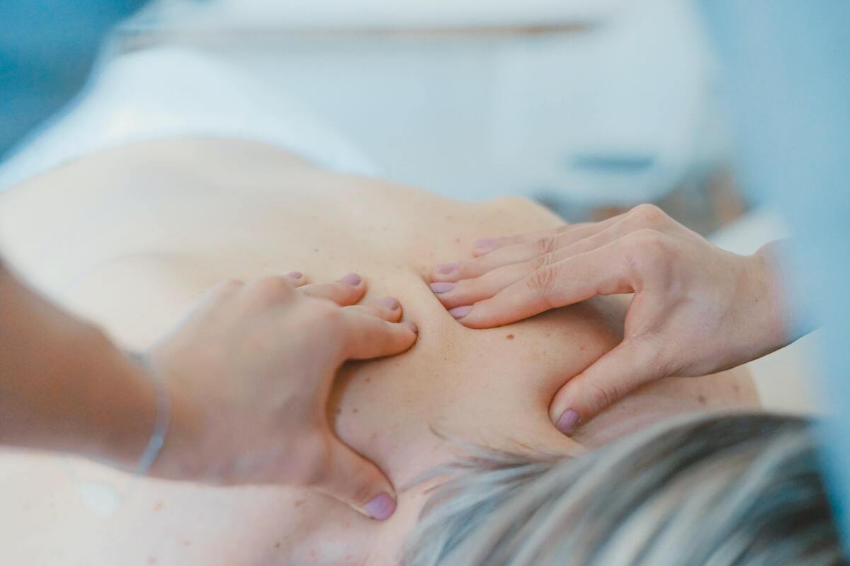 Mulher fazendo massagem nas costas de outra mulher.
