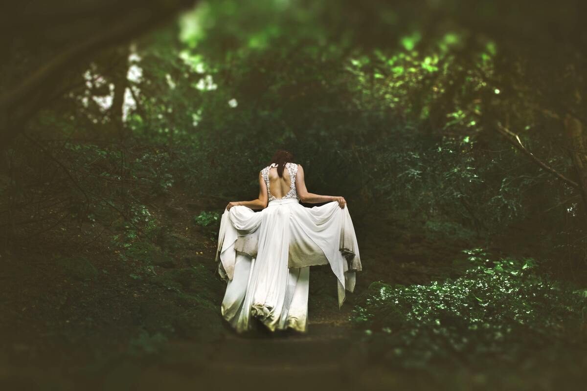 Mulher usando vestido branco em uma floresta.