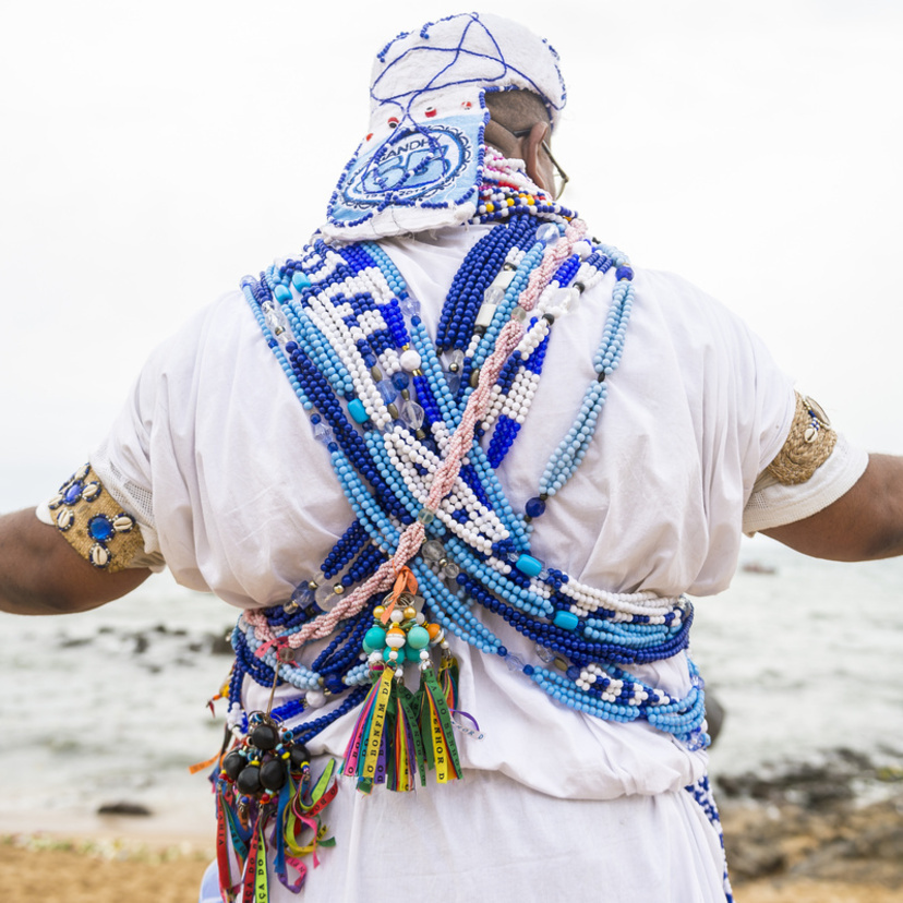 Homem trajado de branco usando cordões da Umbanda.