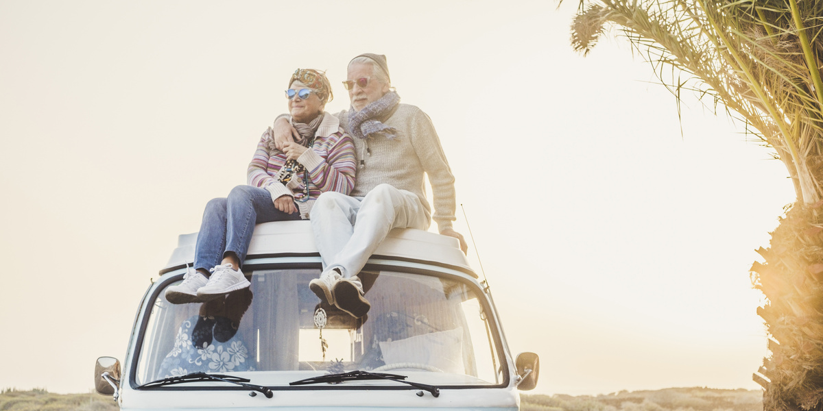 Um casal de idosos em cima de um carro.