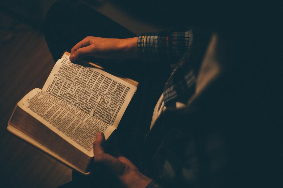 Homem passando as páginas de uma bíblia. 