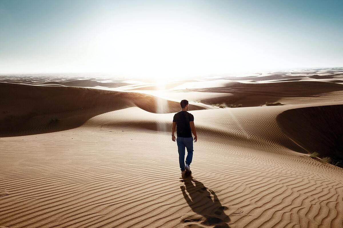 Homem andando em um deserto.