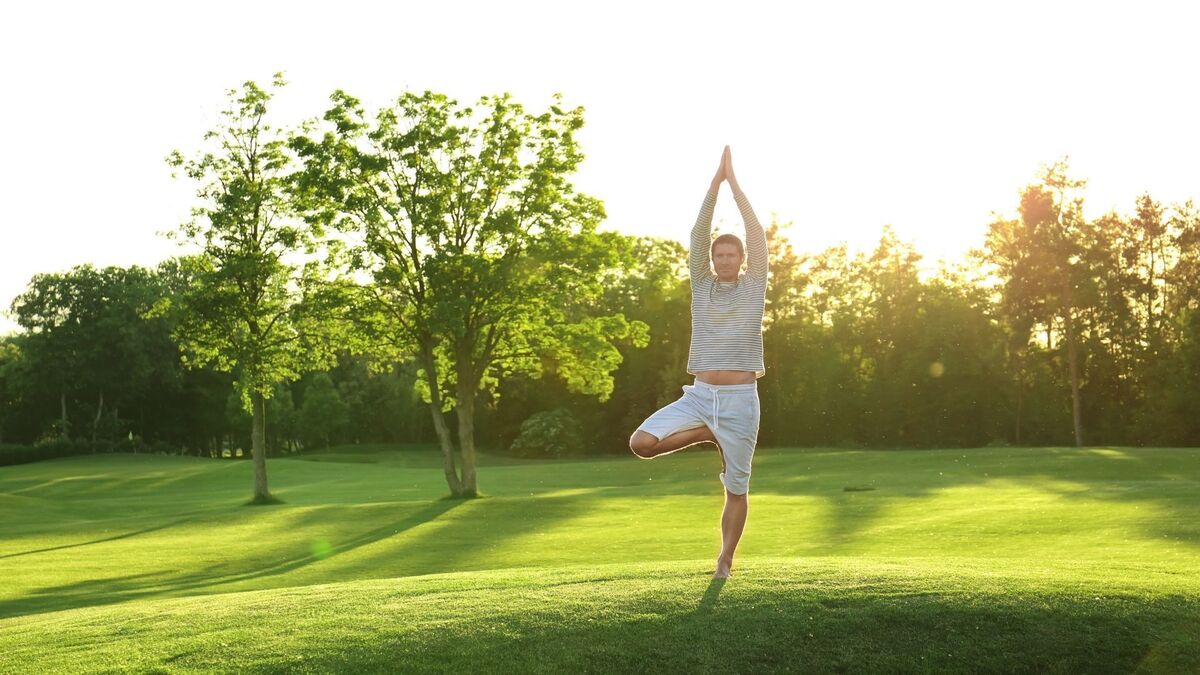 Homem fazendo Yoga no gramado.