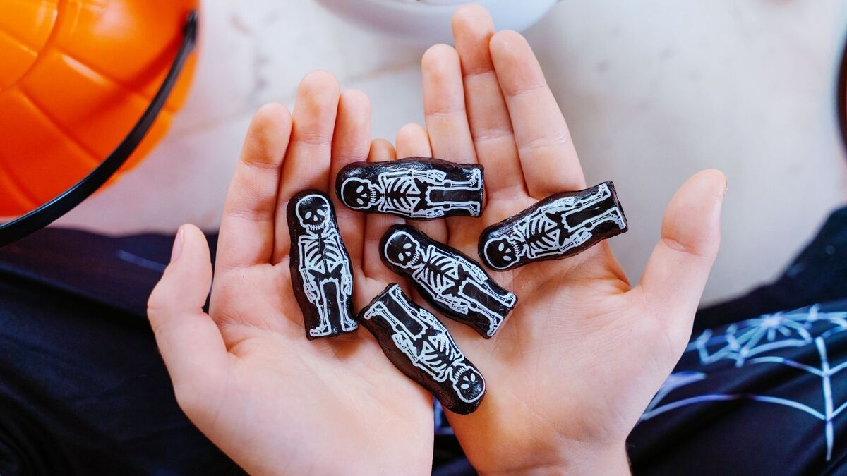 Mãos segurando esqueletos em miniatura.