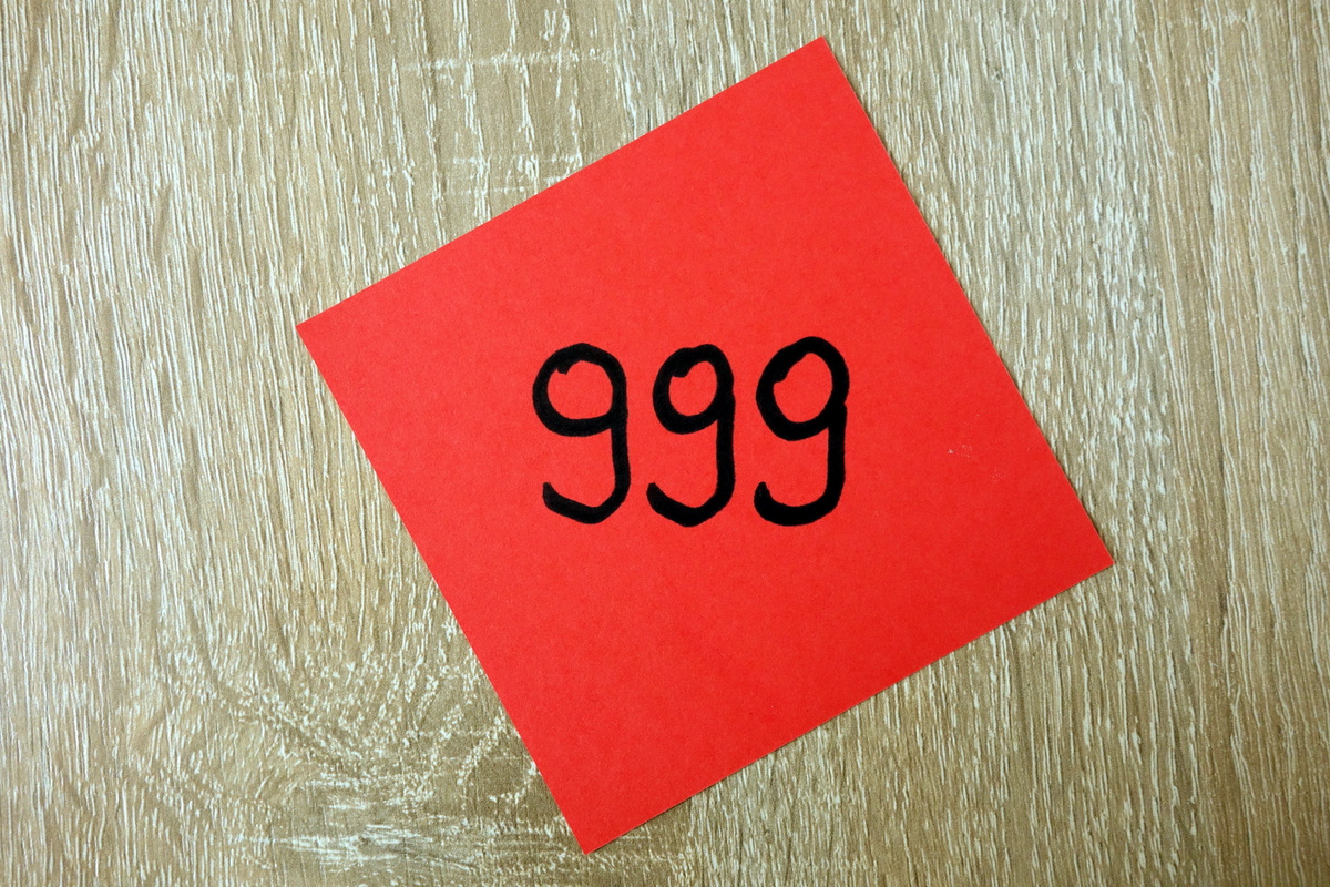 Número 999 escrito com caneta preta em um papel vermelho.
