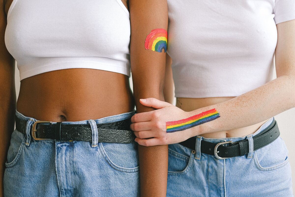 Mulheres com bandeira gay pintada no braço.