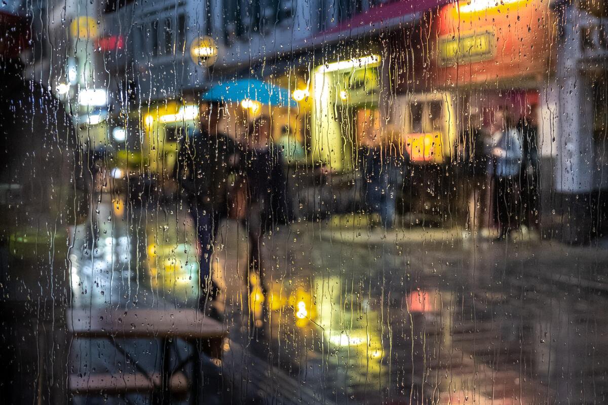 Chuva caindo enquanto casal anda na rua.