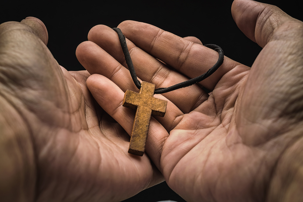 Crucifixo de madeira nas mãos de uma pessoa.