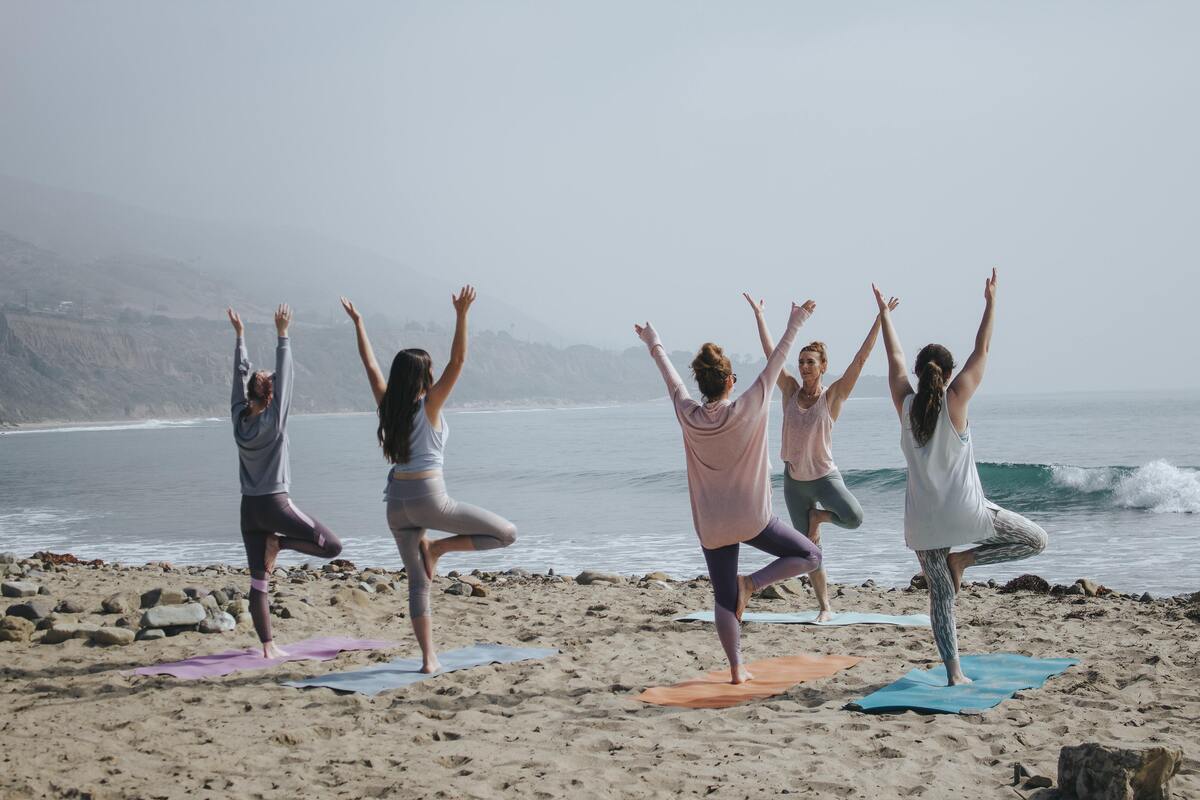 Pessoas fazendo pose de yoga na praia.