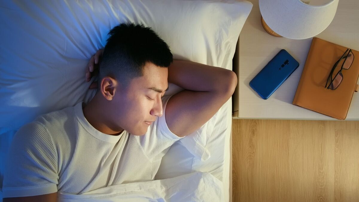 Homem dormindo com celular do lado.