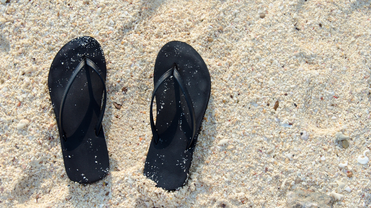 Par de chinelos na areia.
