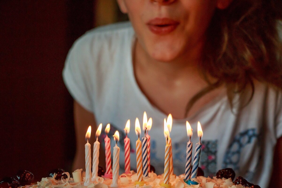 Mulher prestes a soprar velas em bolo de aniversário.