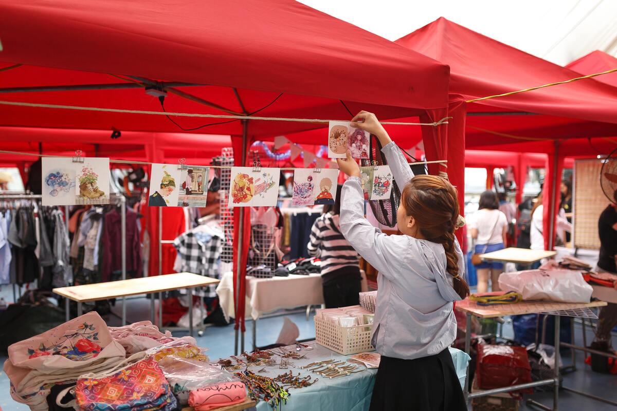 Cliente feminina escolhendo ilustração de varal em uma barraca de feira.
