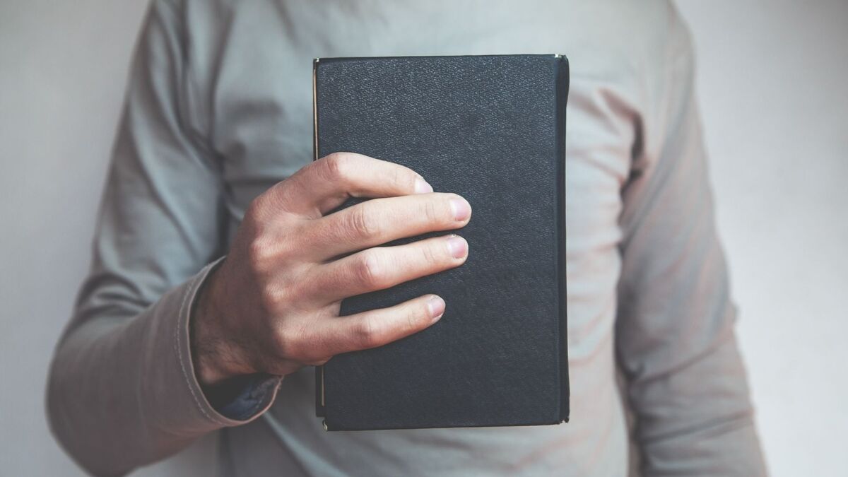 Homem segurando uma bíblia no peito.