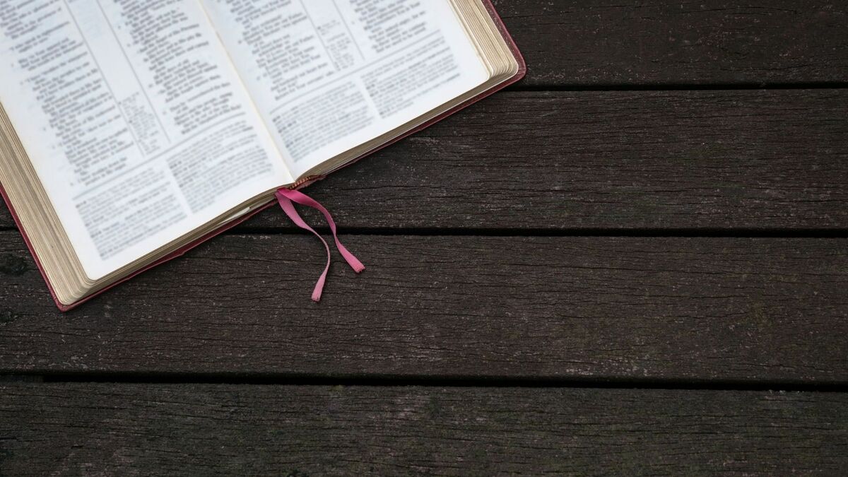 Bíblia aberta em cima de uma mesa de madeira.