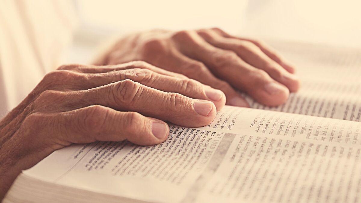 Duas mãos em cima de uma bíblia.
